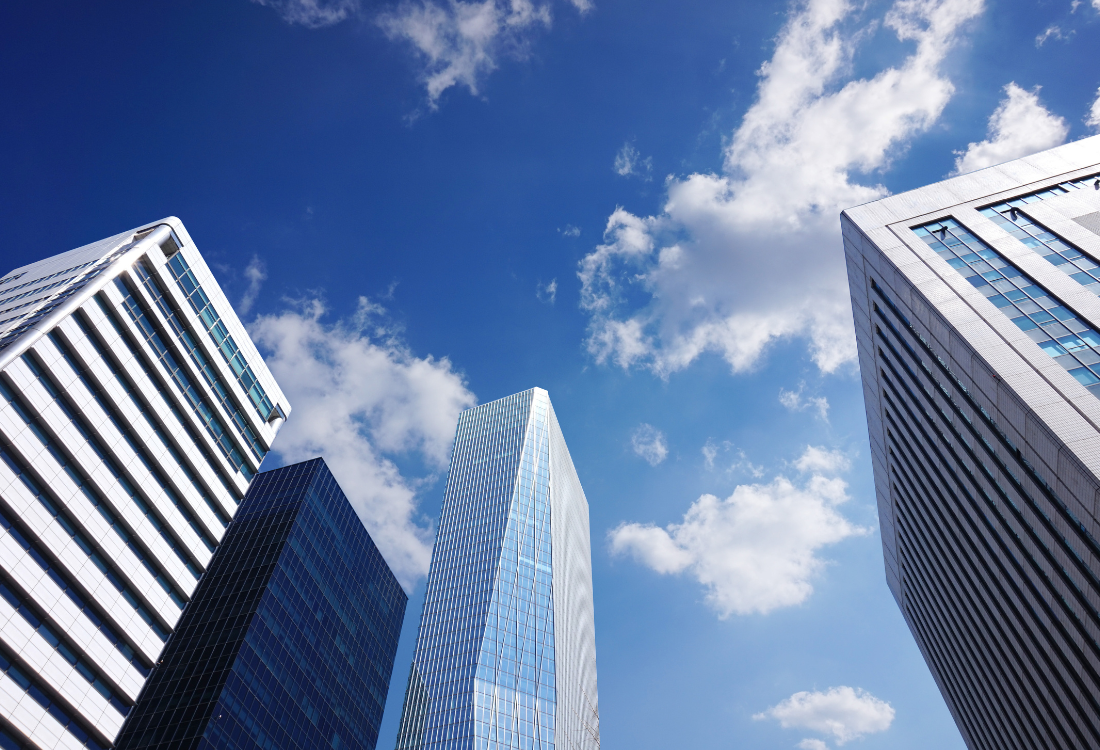 Modern cityscape of four high-rise buildings against a blue sky, illustrating the professional structure and advantages associated with the benefits of a limited company.