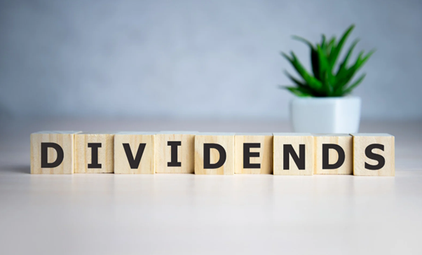 Paying dividends to family members concept shown with “dividends” text on cube dice and financial background representing income distribution and tax planning.